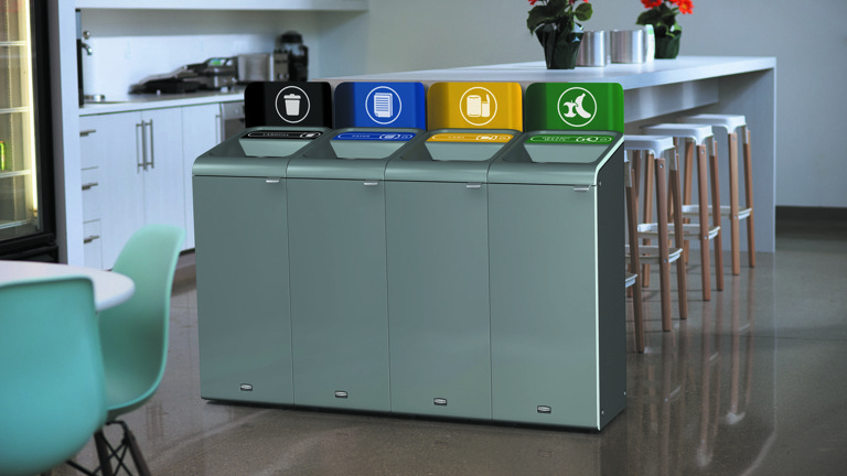 Modern recycling and waste bins in an office kitchen with color-coded labels for trash