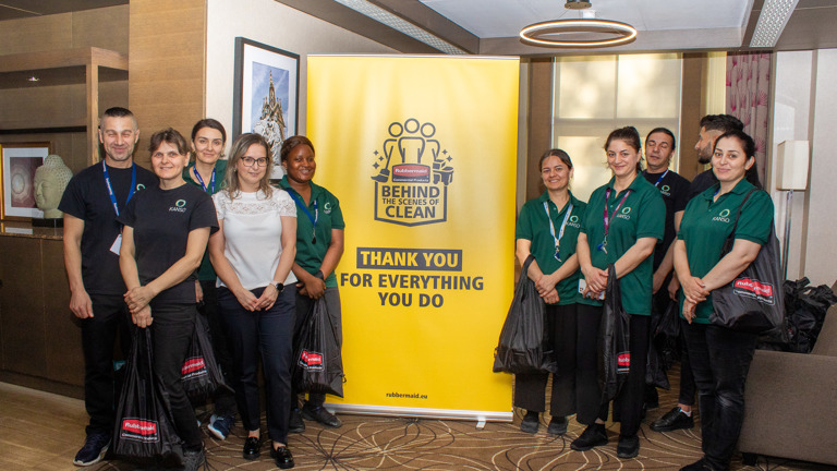 Group of hotel staff standing in front of a banner reading ""Thank You For Everything You Do"" with smiles